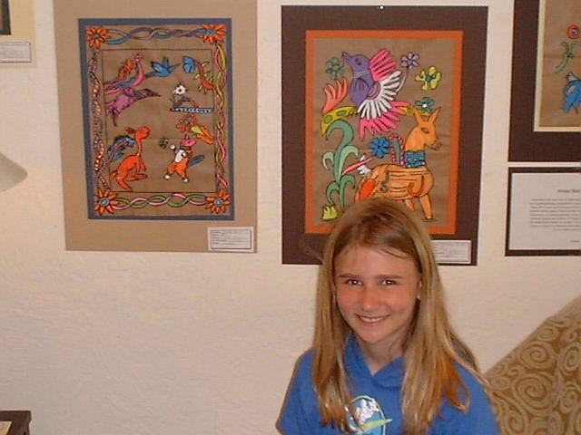 A child proudly standing before a wall of art